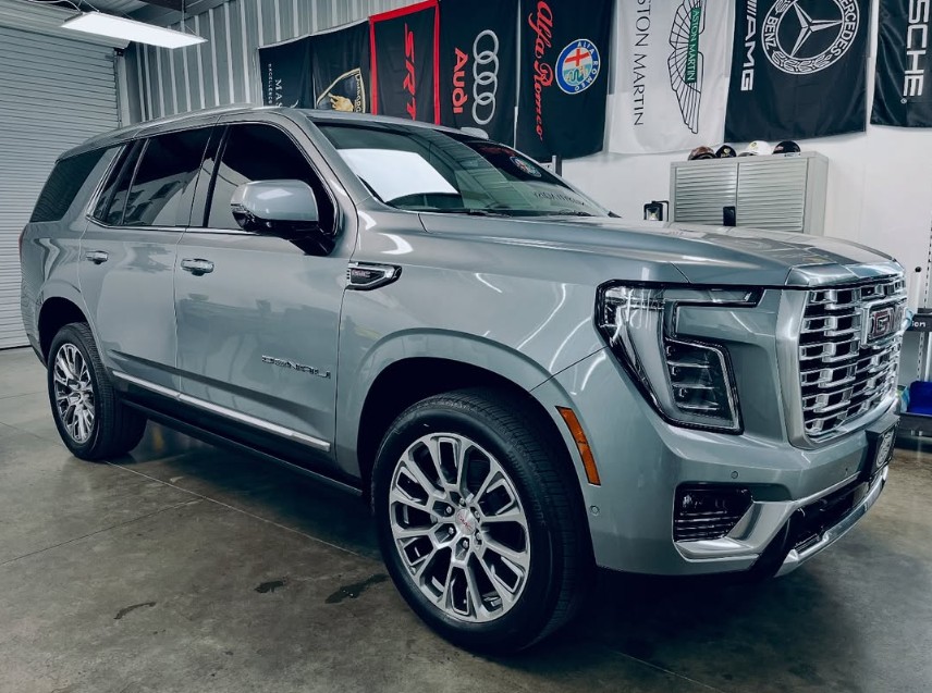 Silver luxury SUV parked indoors with branded banners in the background.