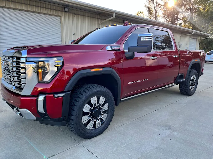 Red Denali HD truck parked in driveway, showcasing modern design and robust features under the sunlight. Window Tinting Near Auburn I-85 corridor.
